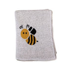 Cobija de algodón para bebé con un adorable diseño tejido de abejas y panales sobre un fondo color miel.