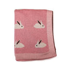 Cobija de algodón para bebé con un tierno diseño tejido de conejitos blancos sobre un fondo color pastel.
