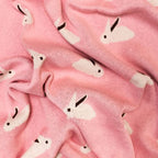 Bebé durmiendo una siesta tranquilamente, abrazado a su suave cobija con diseño de conejos.