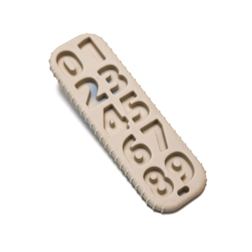 Primer plano de los 'botones' con números y símbolos en relieve de la mordedera de control remoto, diseñados para masajear las encías.